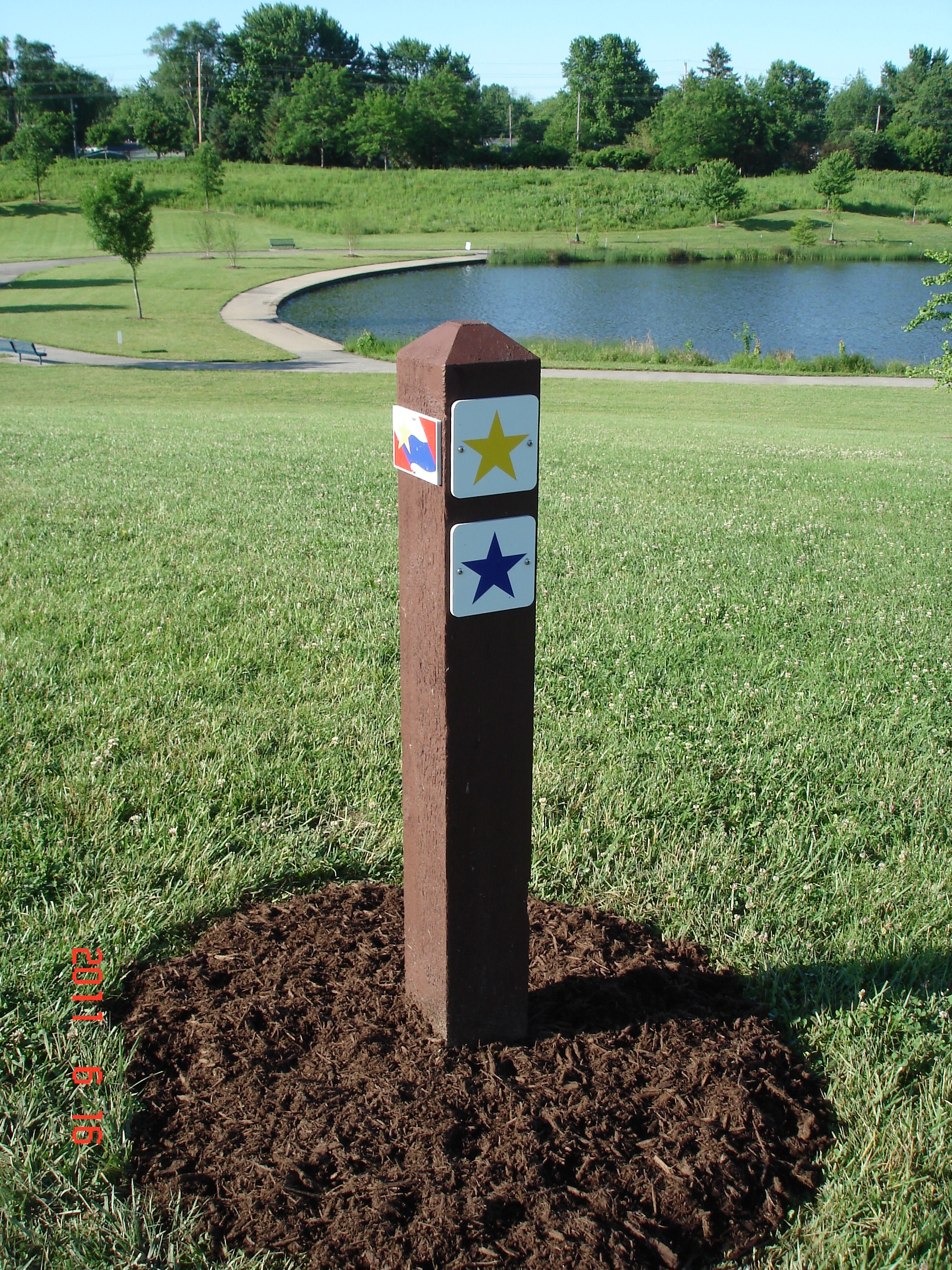 A wooden post with a yellow start and a blue star in the grass